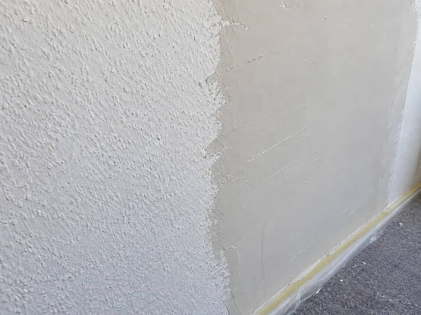 Raufaserwand zur Hälfte glatt gespachtelt mit sichtbarem Übergang zur körnigen Struktur, Malerbetrieb Rekowski Magdeburg